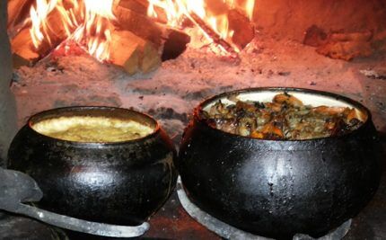 Lonci od lijevanog željeza s hranom u ruskoj pećnici